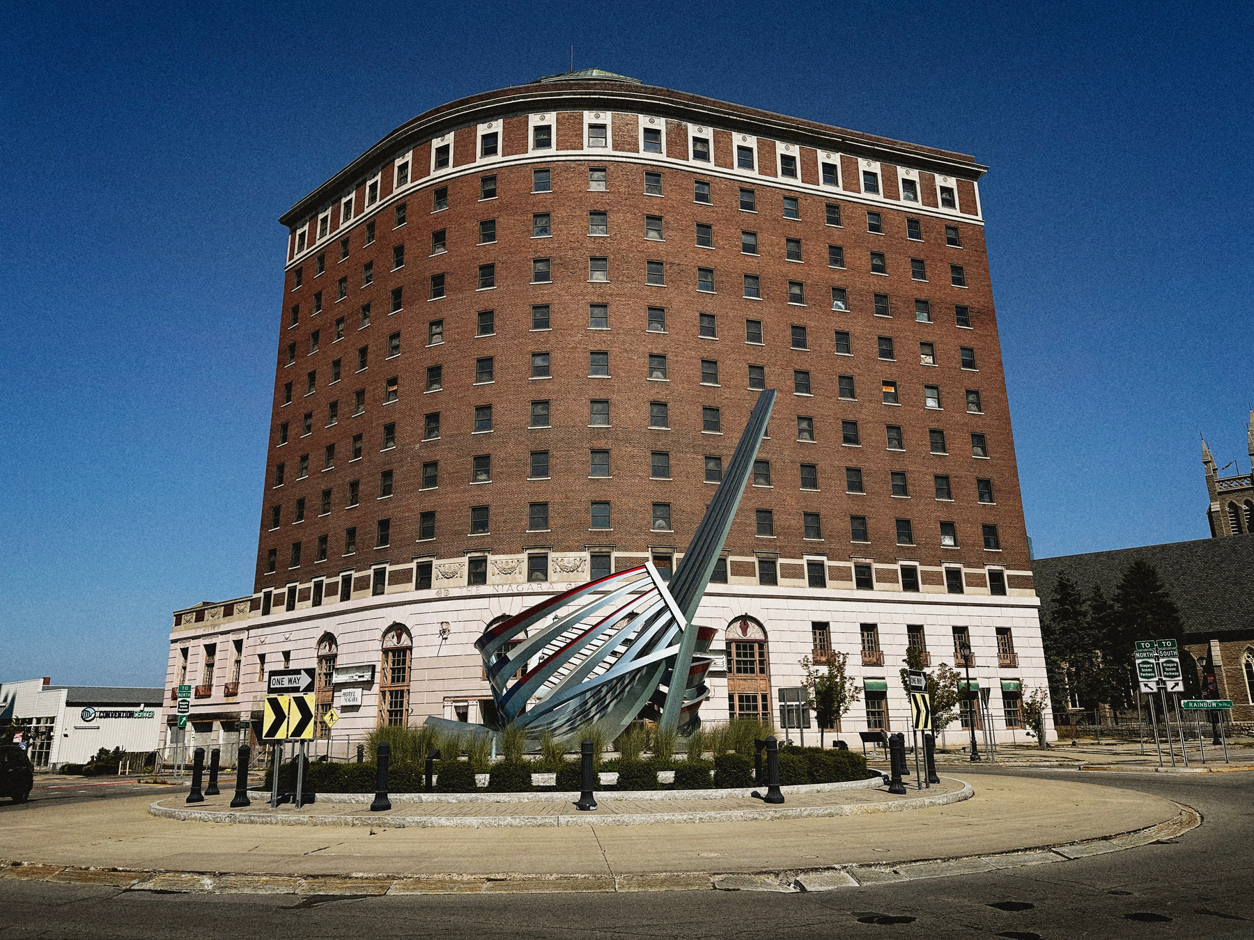 A brick building with a sculpture in the foreground. 